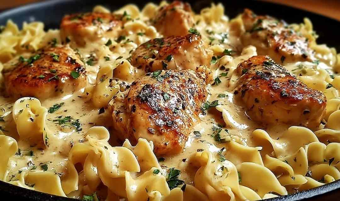 One pan creamy garlic butter chicken with egg noodles in a skillet garnished with fresh parsley
