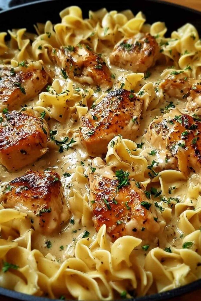 One pan creamy garlic butter chicken with egg noodles in a skillet garnished with fresh parsley