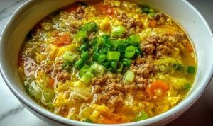 One-pot egg roll soup with ground pork, green onions, and sesame seeds in a white bowl