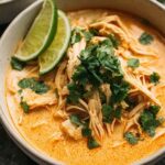 Easy Thai chicken soup in a white bowl with fresh cilantro and red pepper flakes