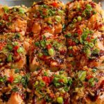 Spicy salmon sushi bake in a white casserole dish topped with avocado, cucumber, green onions, and sesame seeds