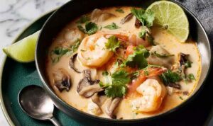 The Best Thai Coconut Soup A bowl of Thai coconut soup with chicken, mushrooms, and red bell pepper garnished with fresh cilantro and a lime wedge