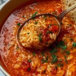 A bowl of hearty tomato rice soup topped with fresh basil on a rustic wooden table
