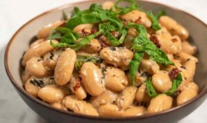 Tuscan Marry Me Butter Beans in a skillet with creamy sun-dried tomato sauce and fresh basil