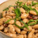 Tuscan Marry Me Butter Beans in a skillet with creamy sun-dried tomato sauce and fresh basil