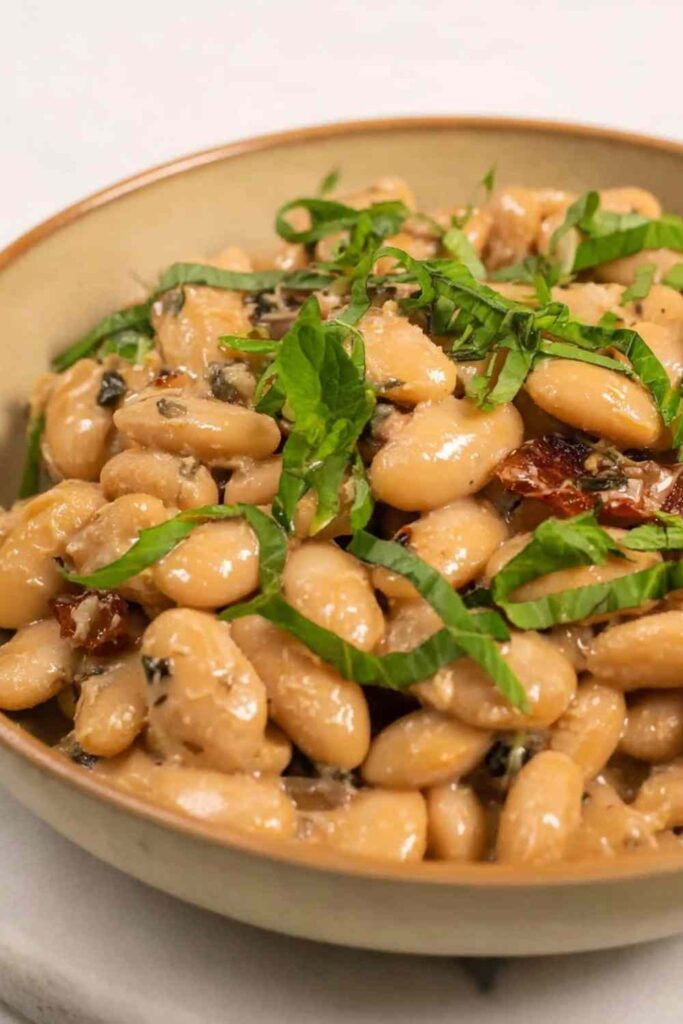Tuscan Marry Me Butter Beans in a skillet with creamy sun-dried tomato sauce and fresh basil