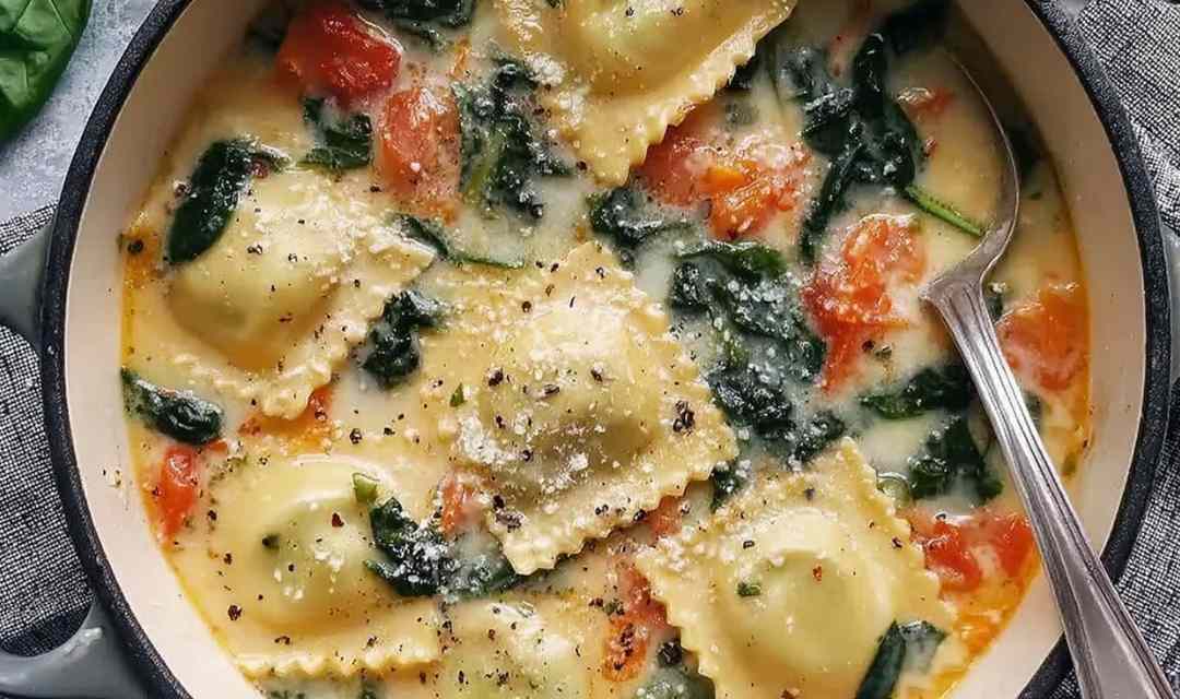 Tuscan ravioli soup in a white bowl topped with Parmesan cheese and wilted kale