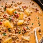 Creamy Tuscan sausage potato soup in a white bowl topped with Parmesan cheese and fresh kale