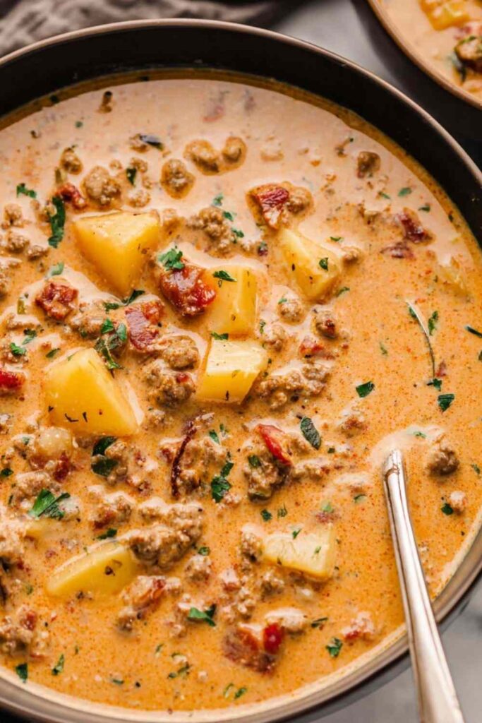 Creamy Tuscan sausage potato soup in a white bowl topped with Parmesan cheese and fresh kale