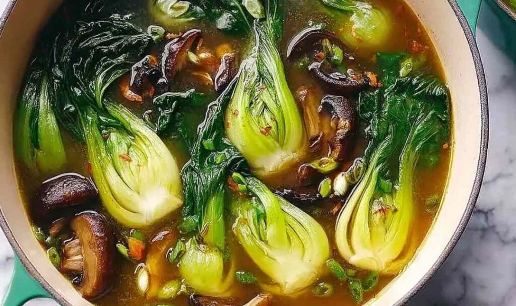 Warming bok choy soup with garlic and ginger in a white bowl garnished with green onions and sesame seeds
