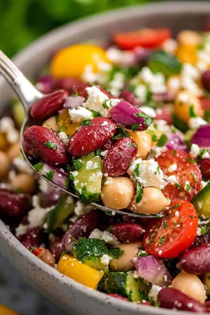 Zesty Mediterranean Bean Salad with Feta 6 Zesty Mediterranean bean salad with chickpeas, feta, olives, and fresh herbs in a large white bowl