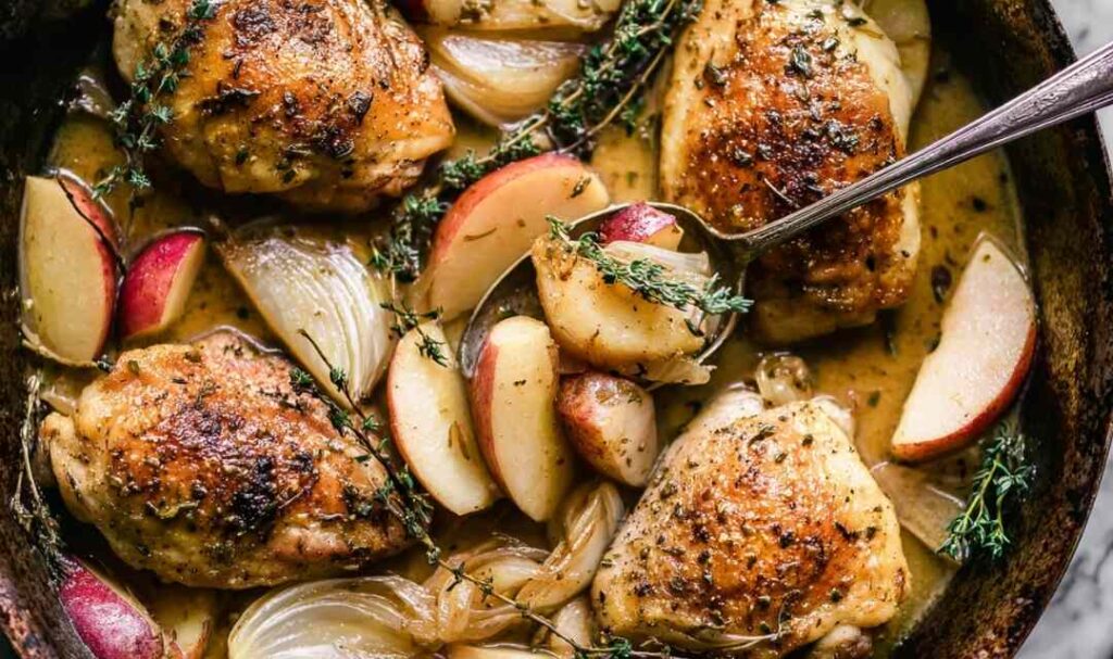 Apple chicken sheet pan dinner with caramelized brown sugar apples and onions on a rimmed baking sheet