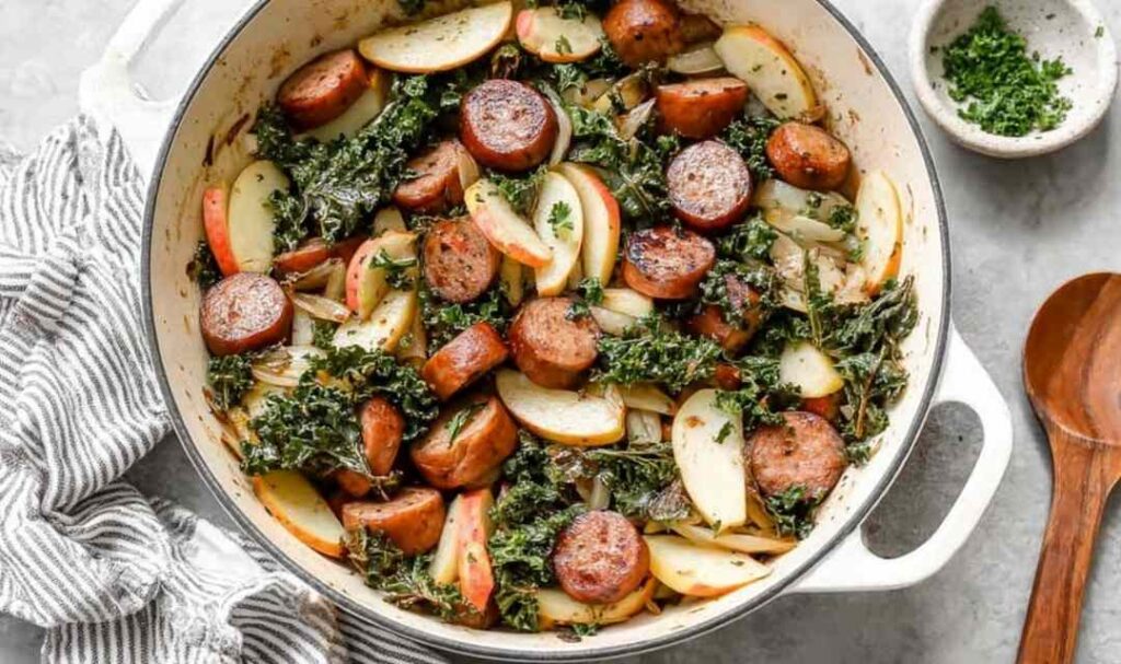 Apple chicken sausage skillet with caramelized apples and wilted kale in a cast iron pan