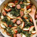 Apple chicken sausage skillet with caramelized apples and wilted kale in a cast iron pan