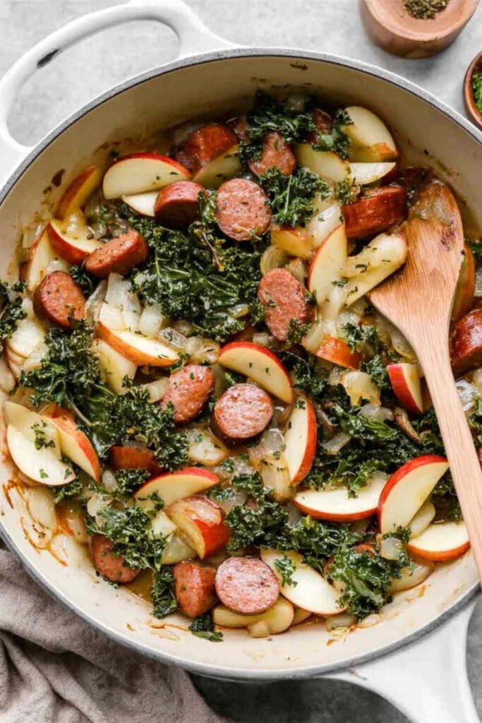 Apple chicken sausage skillet with caramelized apples and wilted kale in a cast iron pan