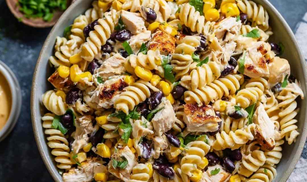 BBQ chicken pasta salad in a large white bowl with corn, red bell pepper, and fresh cilantro garnish