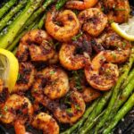 Blackened shrimp and asparagus skillet in a pan garnished with lemon slices and fresh parsley
