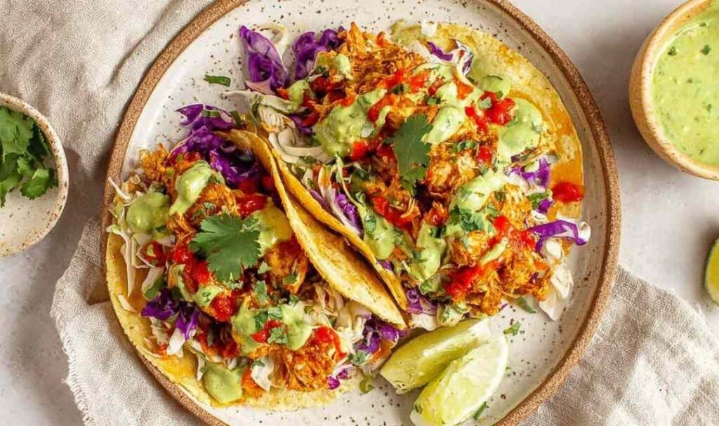 Homemade cantina chicken tacos with juicy shredded chicken, pico de gallo, avocado salsa verde, and cheddar cheese on warm flour tortillas