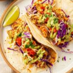 Homemade cantina chicken tacos with juicy shredded chicken, pico de gallo, avocado salsa verde, and cheddar cheese on warm flour tortillas