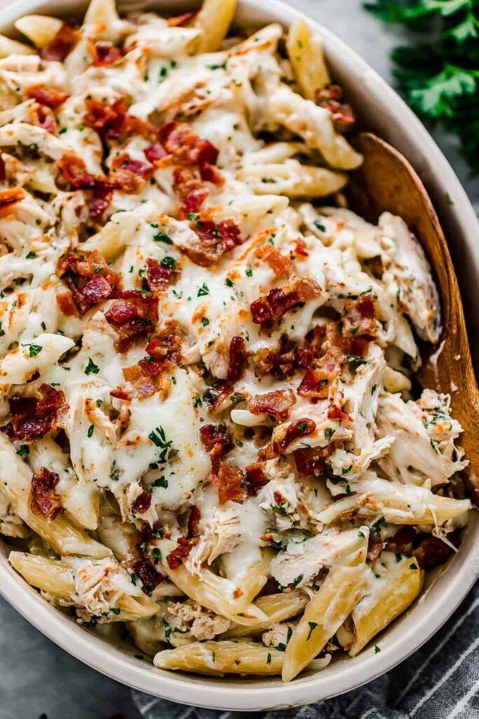 Chicken Bacon Ranch Pasta Bake in a white 9x13 casserole dish with golden melted mozzarella and crispy chopped bacon on top