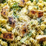 Chicken Caesar pasta salad in a large white bowl with croutons and parmesan
