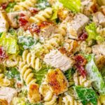 Chicken Caesar pasta salad in a large bowl with croutons, Parmesan and romaine lettuce