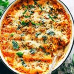 Chicken cannelloni baked in a creamy herb sauce in a white baking dish