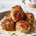 Chicken Cordon Bleu Meatballs with Dijon cream sauce served on a white plate garnished with fresh parsley