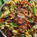 Chicken corn pasta salad in a large white serving bowl with fresh parsley garnish