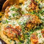 Chicken Florentine in a cast iron skillet with creamy Parmesan spinach sauce and golden seared chicken thighs