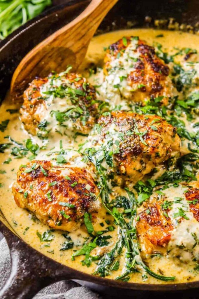 Chicken Florentine in a cast iron skillet with creamy Parmesan spinach sauce and golden seared chicken thighs