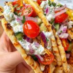 Chicken Gyros Smash Tacos topped with tzatziki, cucumber, cherry tomatoes, and fresh coriander on a wooden board