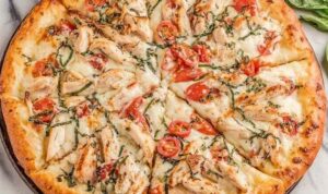 Chicken margherita pizza with grilled chicken slices, fresh basil, and melted mozzarella on a crispy golden crust