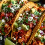 Chicken street tacos on charred corn tortillas topped with white onion, cilantro, and lime wedges