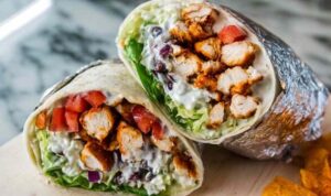 Homemade chipotle chicken burrito cut in half showing juicy marinated chicken, cilantro lime rice, and seasoned black beans inside a flour tortilla