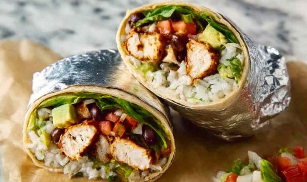 Homemade chipotle chicken burrito cut in half showing juicy marinated chicken, cilantro lime rice, and seasoned black beans inside a flour tortilla