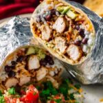 Homemade chipotle chicken burrito cut in half showing juicy marinated chicken, cilantro lime rice, and seasoned black beans inside a flour tortilla