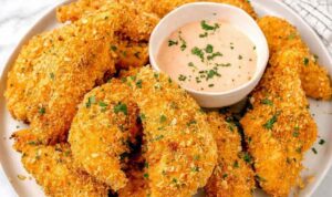 Golden baked cornflake chicken tenders on a wire rack served with creamy homemade special sauce
