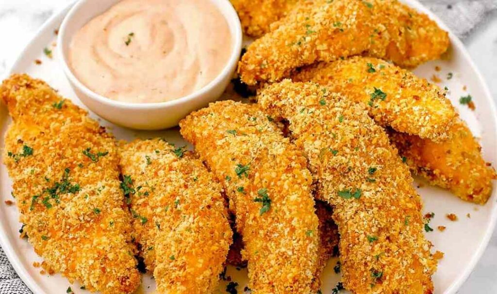 Golden baked cornflake chicken tenders on a wire rack served with creamy homemade special sauce