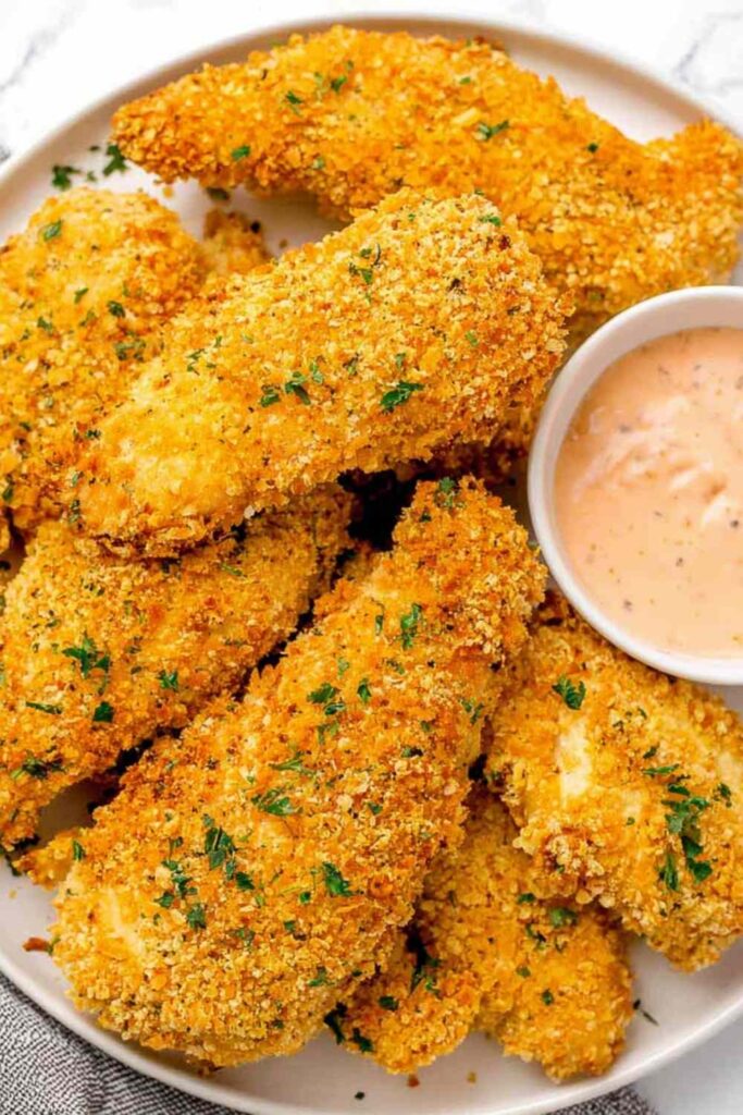 Golden baked cornflake chicken tenders on a wire rack served with creamy homemade special sauce