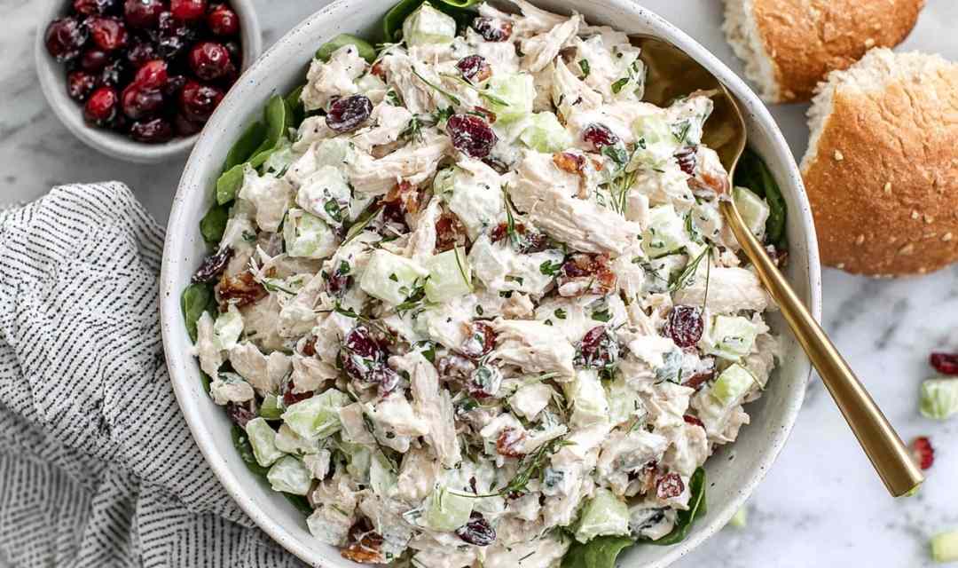 Cranberry chicken salad with dried cranberries, pecans, and apple in a large white bowl