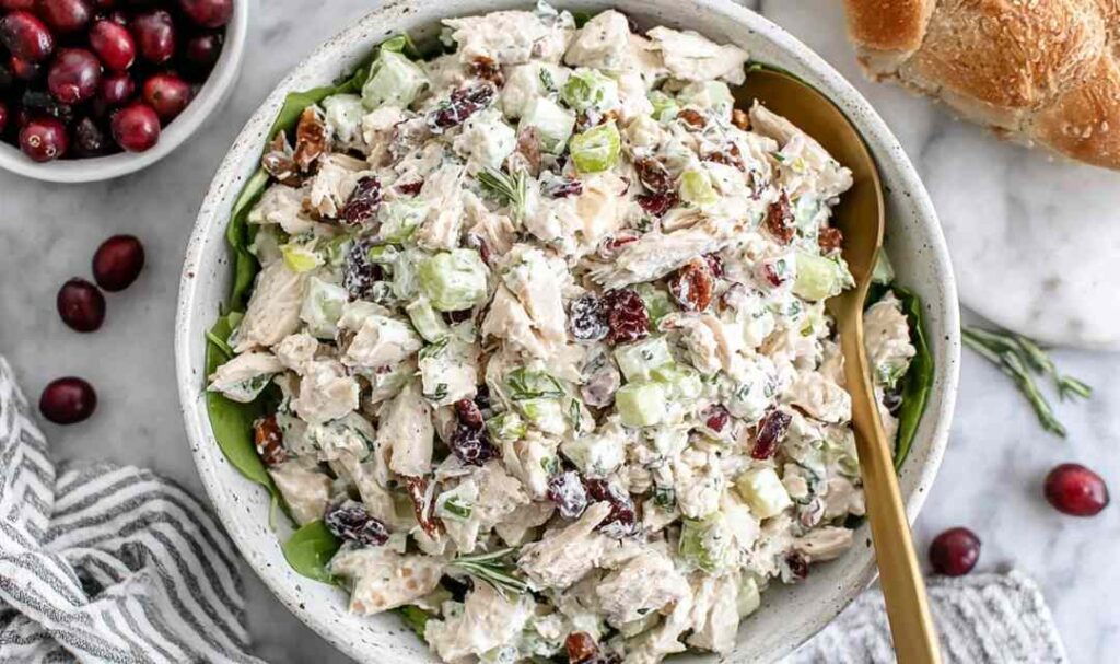 Cranberry chicken salad with dried cranberries, pecans, and apple in a large white bowl
