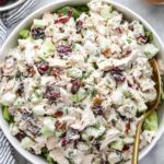 Cranberry chicken salad with dried cranberries, pecans, and apple in a large white bowl