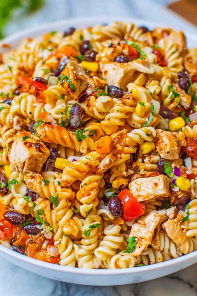 BBQ Chicken Pasta Salad 6 BBQ chicken pasta salad with black beans, corn, and rotini in a large white bowl