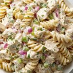 Creamy chicken pasta salad in a large white bowl with fresh parsley garnish