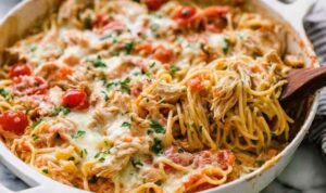 Creamy chicken spaghetti casserole in a white baking dish with golden bubbly mozzarella on top