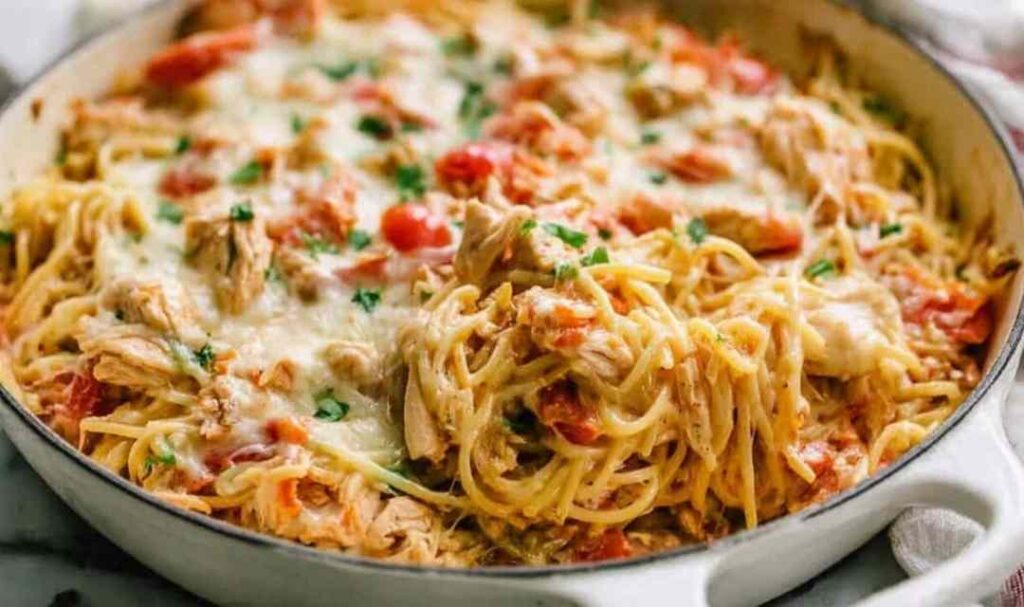 Creamy chicken spaghetti casserole in a white baking dish with golden bubbly mozzarella on top