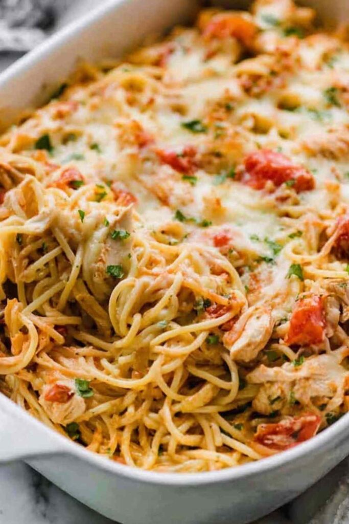 Creamy chicken spaghetti casserole in a white baking dish with golden bubbly mozzarella on top
