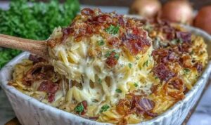 Creamy French onion chicken orzo casserole in a white baking dish topped with golden melted Swiss and Parmesan cheese