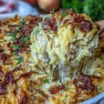 Creamy French onion chicken orzo casserole in a white baking dish topped with golden melted Swiss and Parmesan cheese